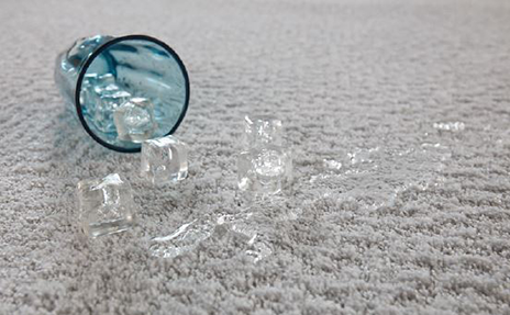 glass of water and ice spilled on waterproof white carpet